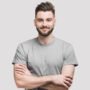 istockphoto-1200677760-612x612 Cheerful young man with crossed hands looking to the camera. Isolated on gray background